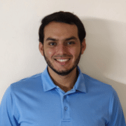 Headshot of a man smiling at the camera wearing a light blue polo shirt